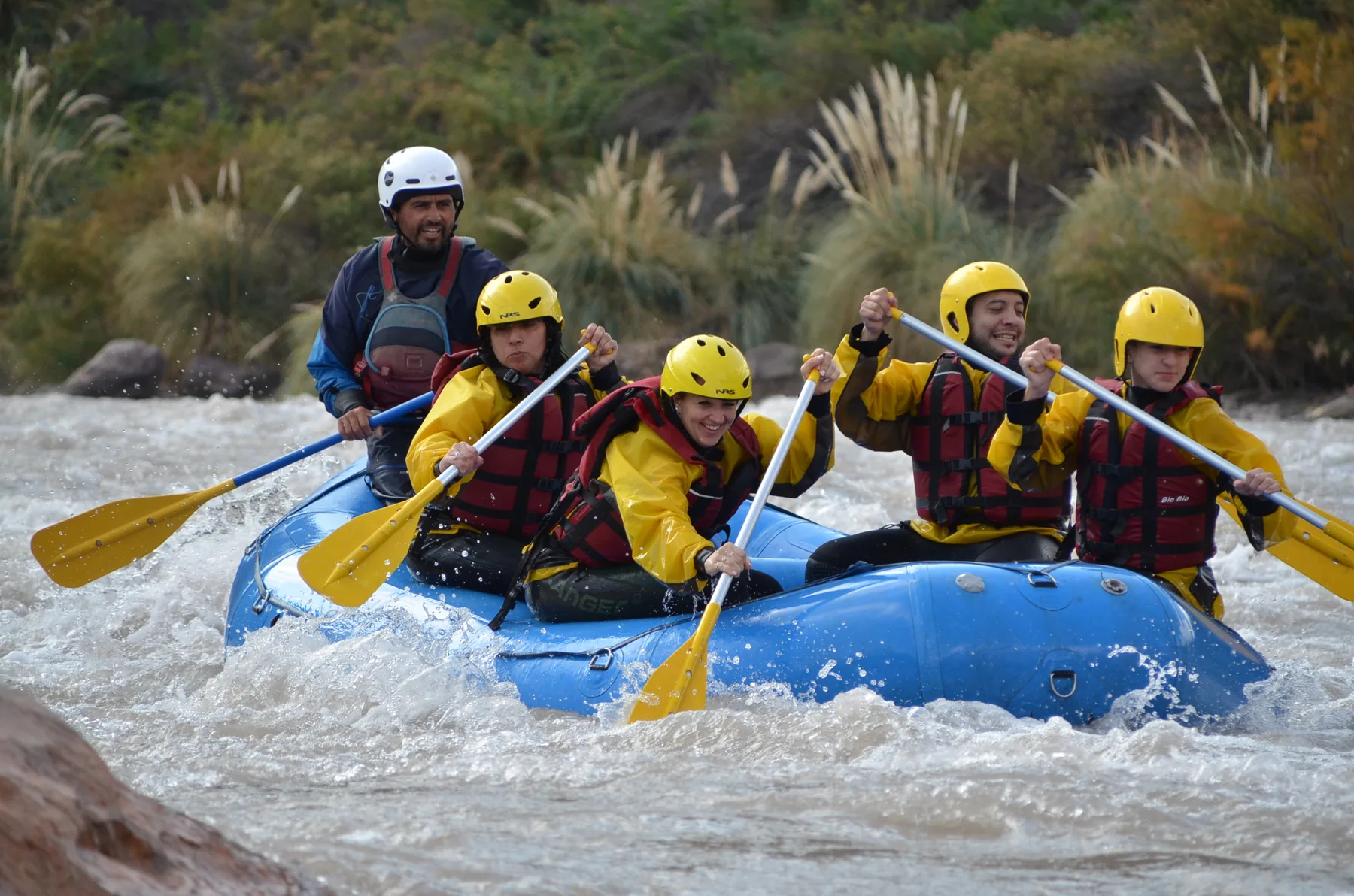 Pasajeros reman en una balsa azul entre los rápidos del Río Mendoza