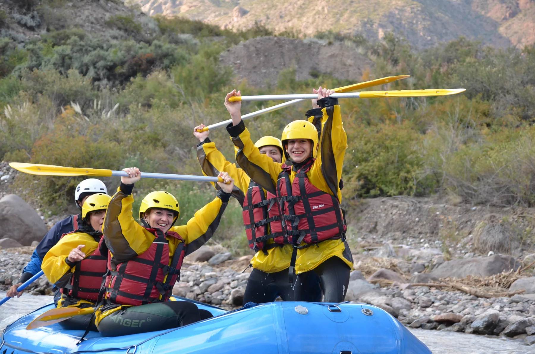 Pasajeros celebran en una balsa azul después de una bajada de rafting